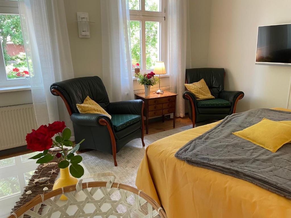 1 dormitorio con 2 sillas, 1 cama y 1 mesa en Ferienwohnungen an der Stadtvilla Rheinsberg en Rheinsberg