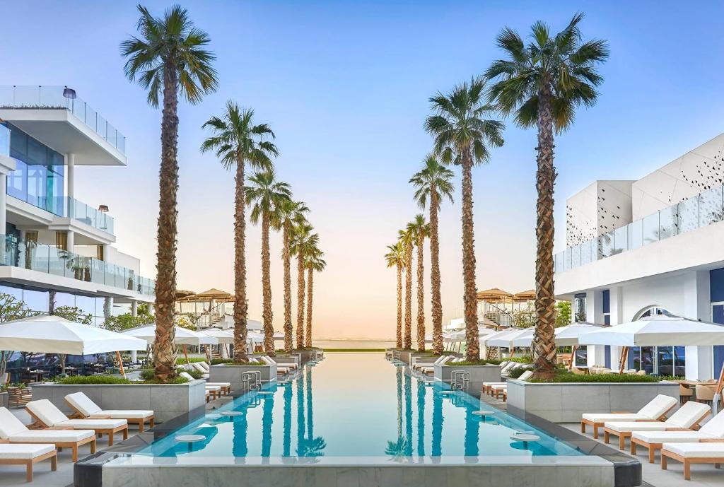 an image of a resort pool with palm trees at FIVE Palm Jumeirah Resort - 2 Bedrooms plus Maids and Private Jacuzzi - ModernLux in Dubai