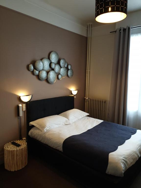 a bedroom with a bed and two lamps and a window at Hotel Le Splendid in Troyes