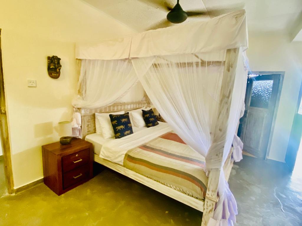 a bedroom with a canopy bed and a wooden nightstand at SUNSET BEACH HAVEN, Entire Villa, Beachfront, Pool, Private in Galle