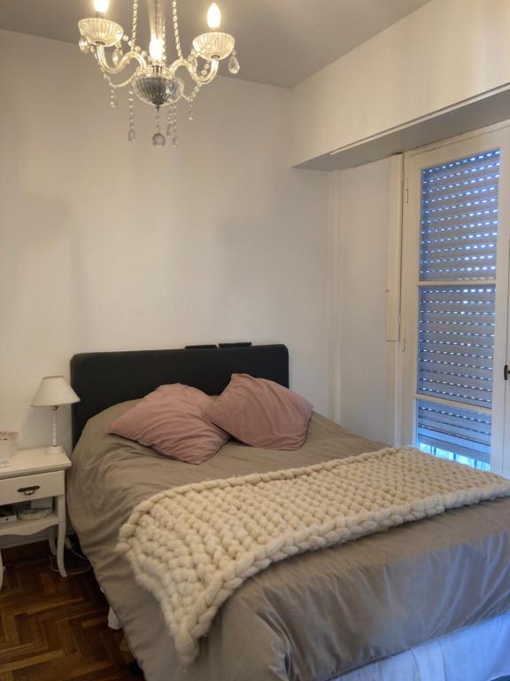 a bedroom with a bed with a chandelier and a window at Departamento en PLAYA GRANDE in Mar del Plata