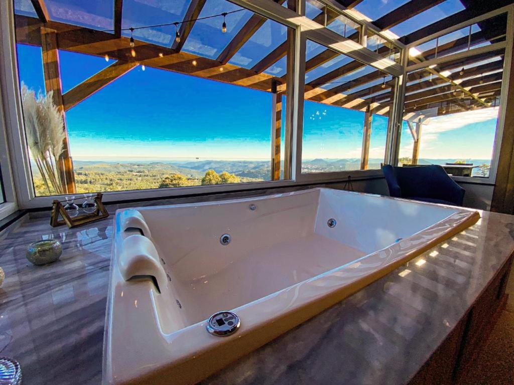 uma grande banheira num quarto com uma grande janela em Josef’s Chalé em Nova Petrópolis