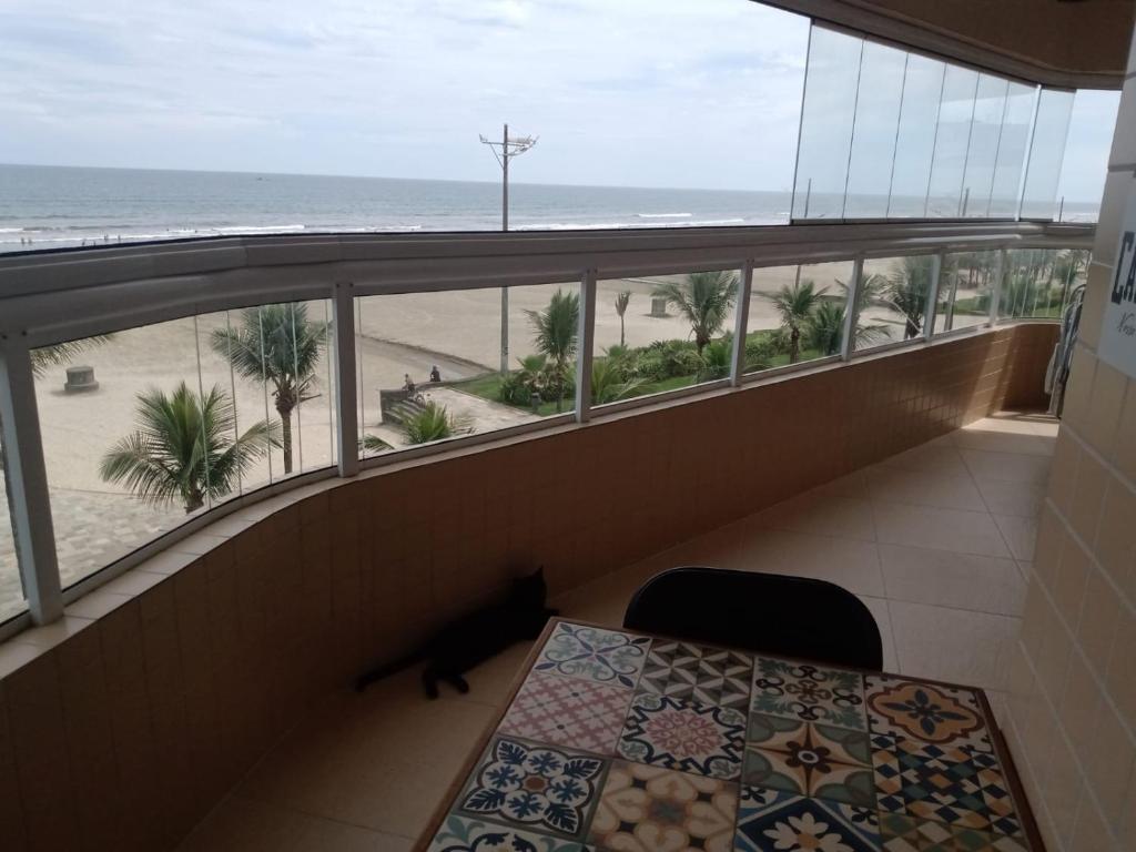 een balkon met een tafel en uitzicht op het strand bij Frente pro mar apartamento completo in Praia Grande