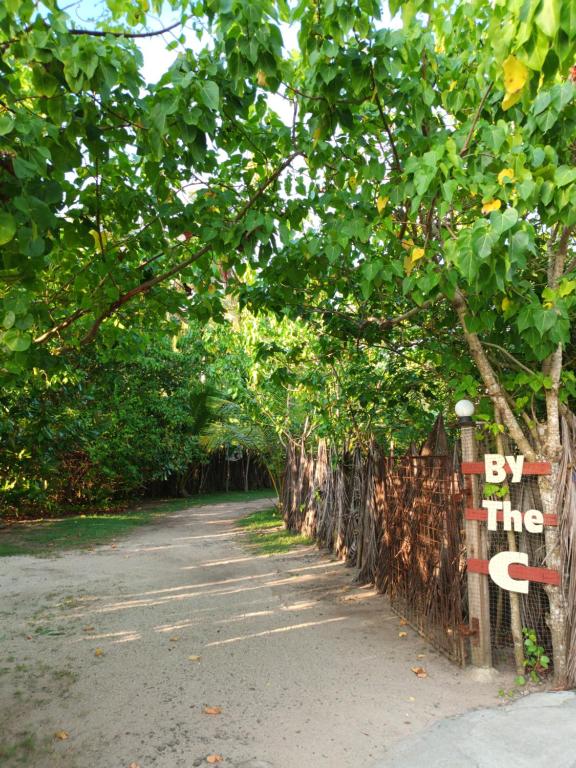 a fence with a sign that says by the trees at By The C' Cabanas in Hikkaduwa