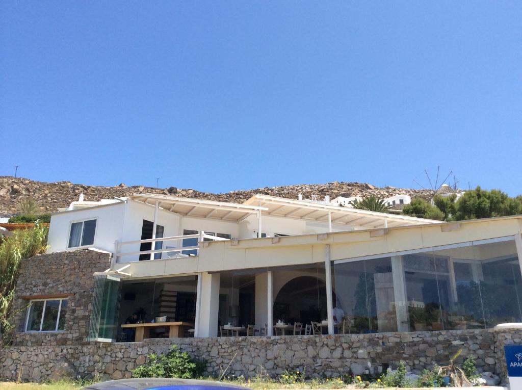 a white house with large windows and a hill at Sailinn Mykonos in Ornos