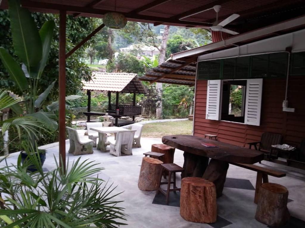 een patio met een tafel, banken en een paviljoen bij Green Season Cottage in Sungai Lembing