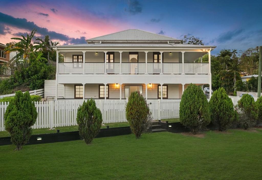 una gran casa blanca con una valla blanca y árboles en Homestead on the Range - Sleeps 12, en The Range