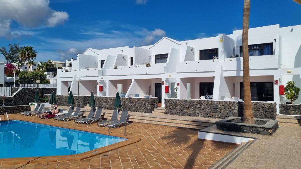 un gran edificio blanco con una piscina frente a él en Princesa Ico en Puerto del Carmen