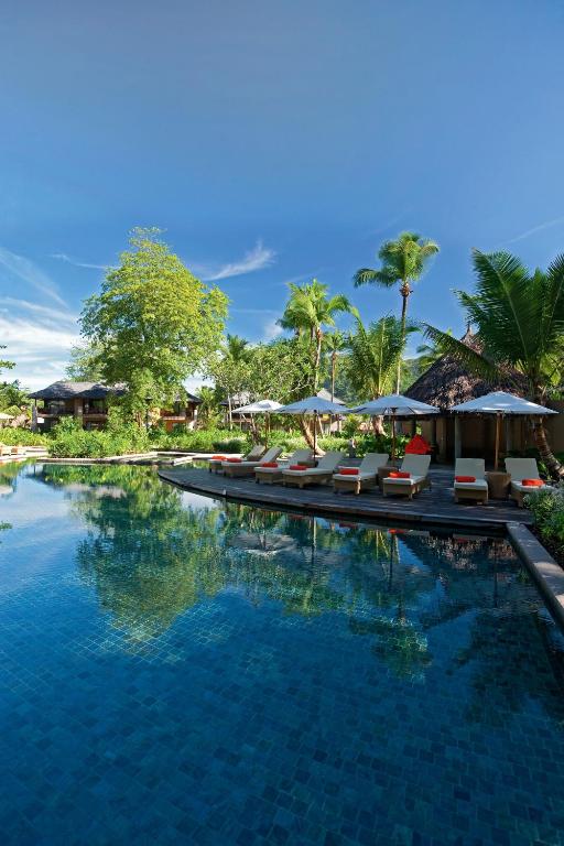 a swimming pool with lounge chairs and umbrellas at Constance Ephelia in Port Glaud