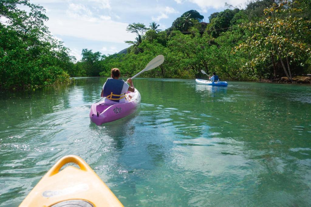 two people are kayaking down a river on a river at Constance Ephelia in Port Glaud