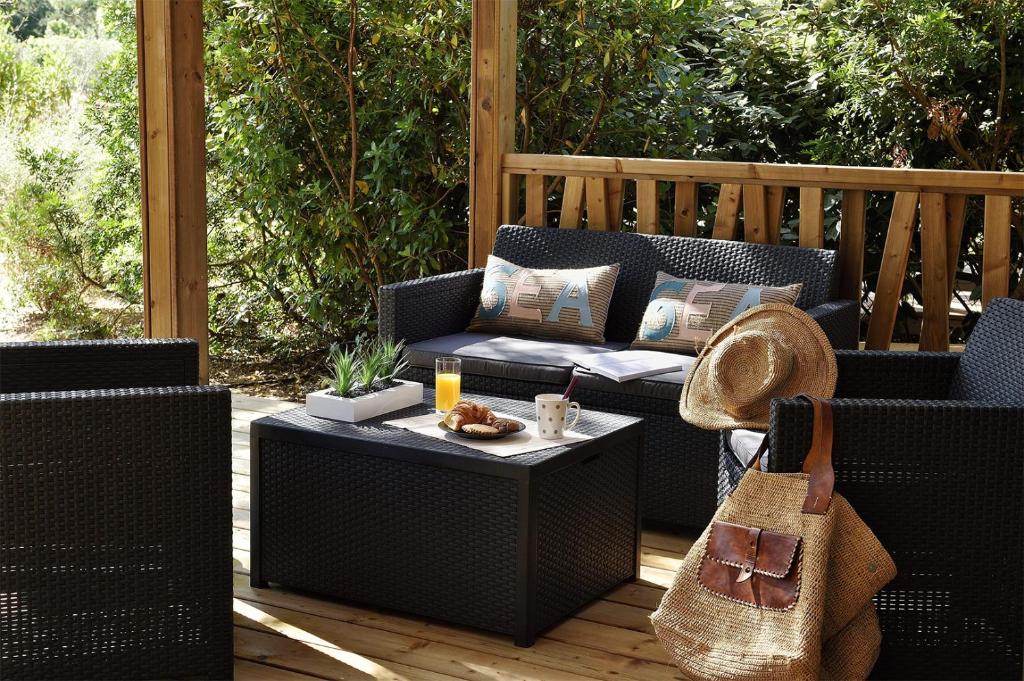 a patio with two wicker chairs and a table at Résidence & Hotel U Livanti ECOLABEL in Propriano