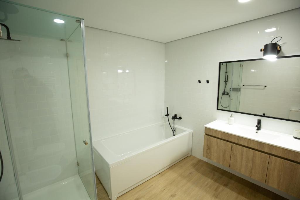 une salle de bain avec une baignoire, un lavabo et un miroir dans l'établissement Casa dos Gatos, à Lourinhã