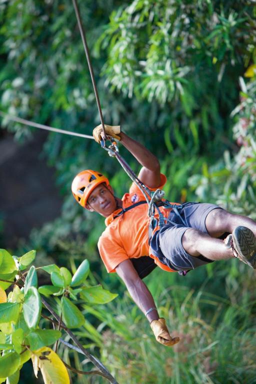a man on a zip line in the jungle at Constance Ephelia in Port Glaud