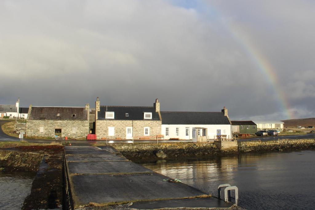 a rainbow in the sky over a group of buildings at The Uyeasound Old Pier Cottage in Belmont