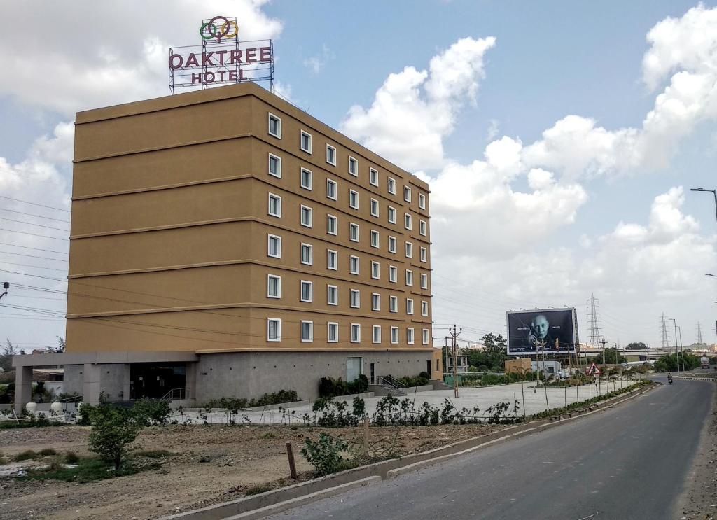 a building with a sign on the top of it at OAKTREE HOTEL in Morbi