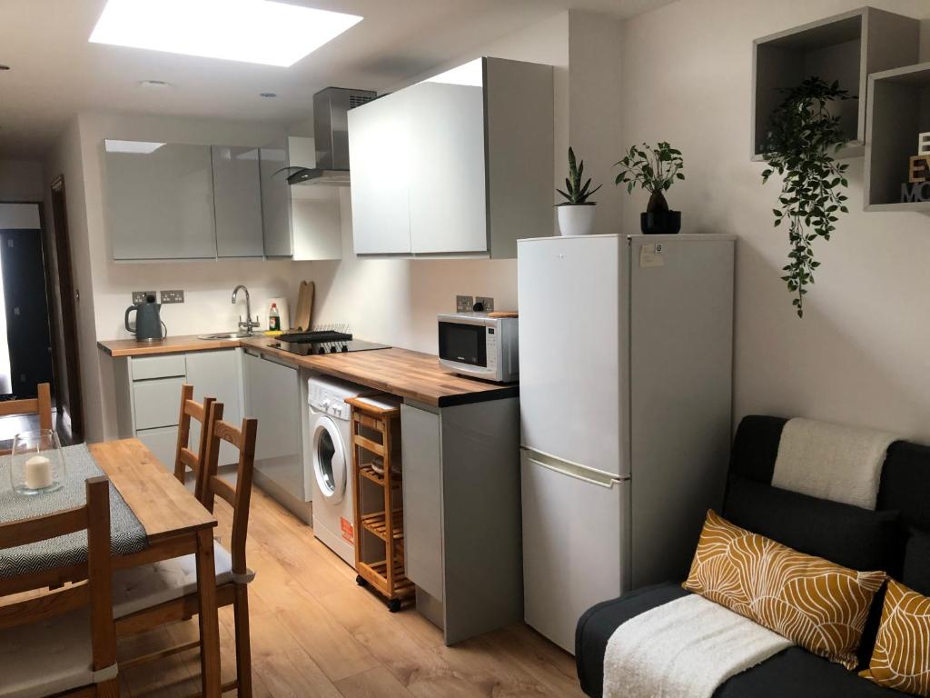 a small kitchen with a white refrigerator and a table and chairs at Modern apartment in Bexley - 25 minutes from central London in Welling