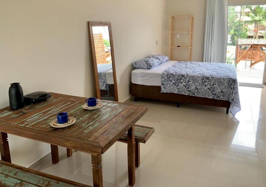 1 dormitorio con cama, mesa y espejo en Loft Jaques, en Palhoça