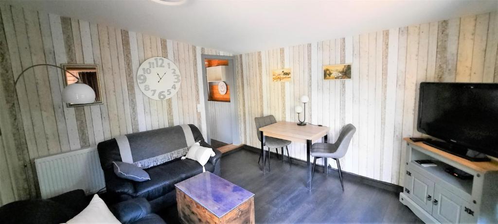 - un salon avec un canapé, une table et une télévision dans l'établissement Kleiner Bungalow Am Wald, à Petershagen