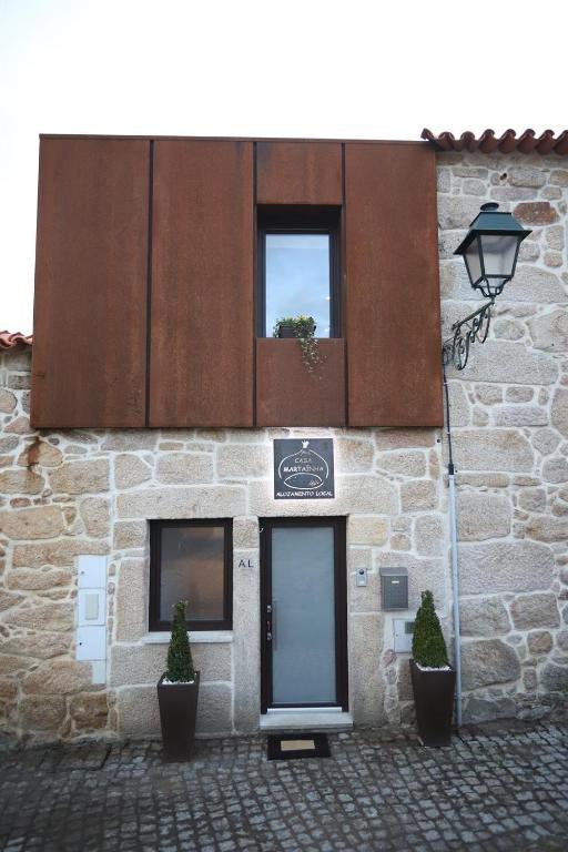 a stone building with a door and two windows at Casa Martaínha in Sernancelhe