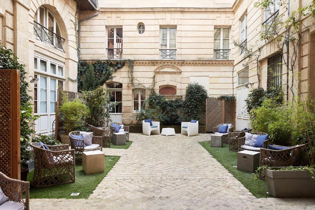 a courtyard of a building with blue pillows and chairs at L'Apparthôtel Particulier Bordeaux in Bordeaux