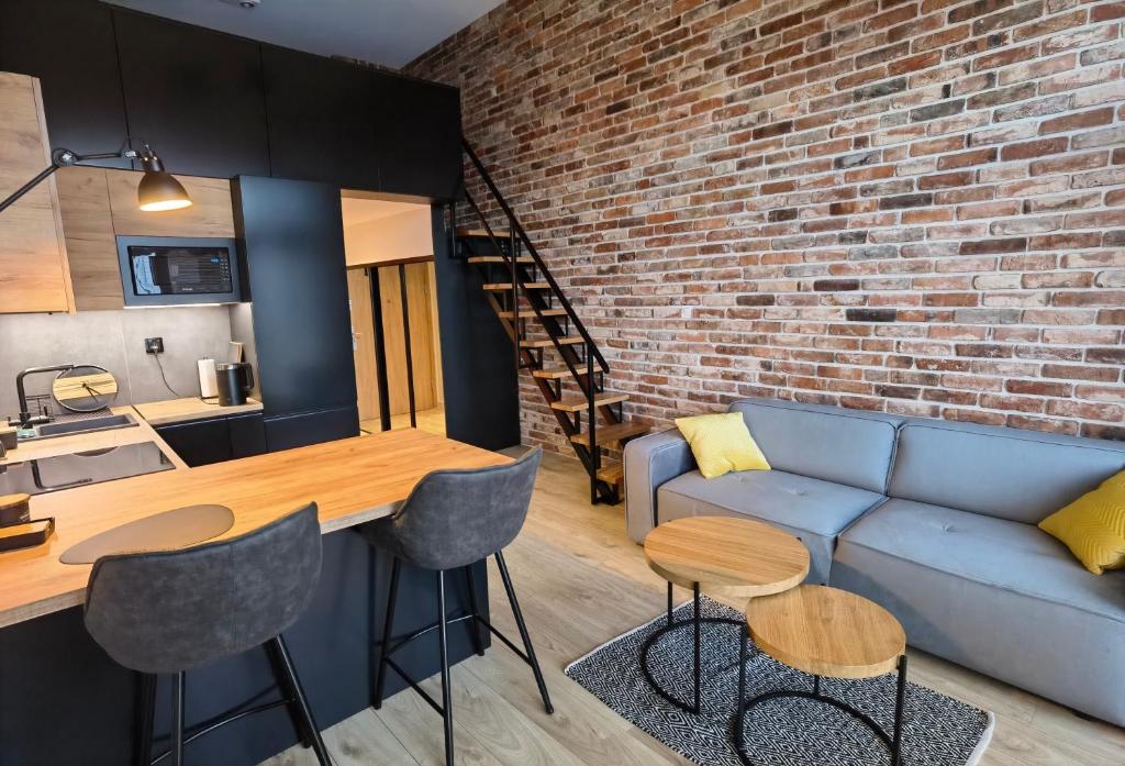 a living room with a blue couch and a brick wall at Apartament Loft Studio Airport blisko lotniska Zarembowicza lotnisko in Wrocław