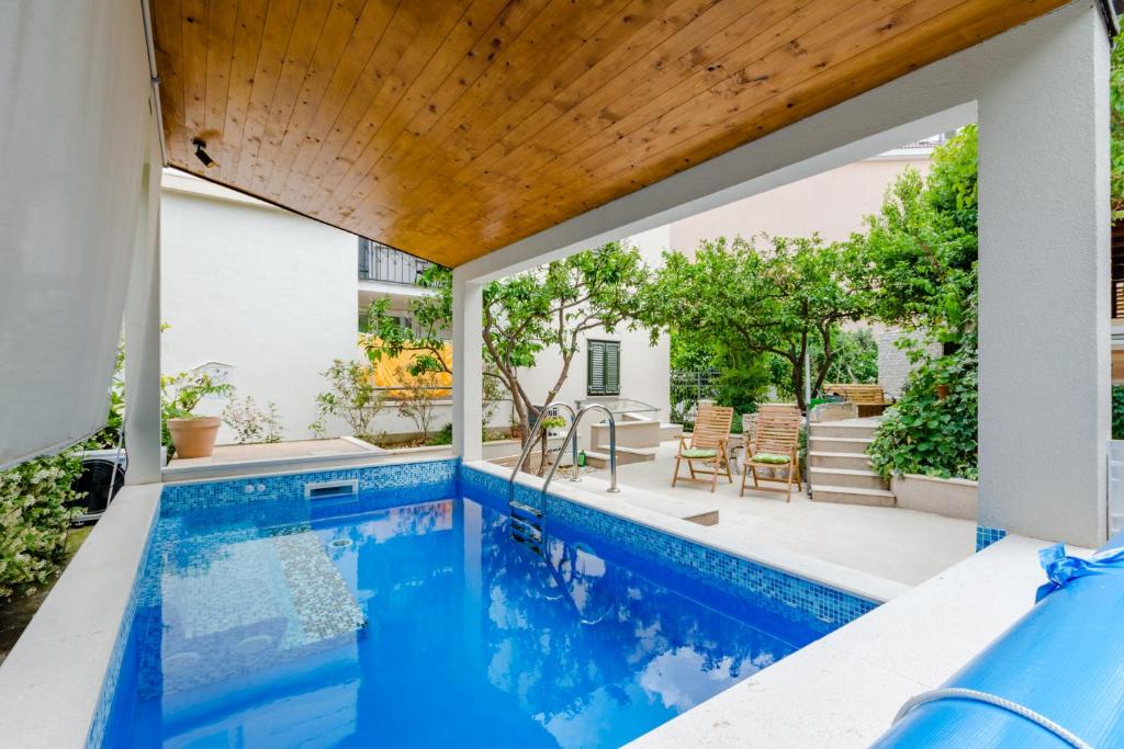an outdoor swimming pool with a wooden roof and a swimming pool at Luxury Villa Roza in Split