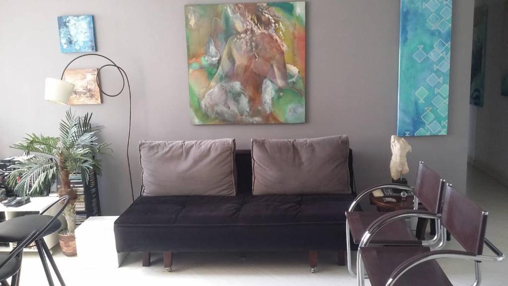 una sala de estar con un sofá negro y una pintura en MADONNA FLAT Qto e Sala em IPANEMA Ótimo para 2 mais 2 pessoas!, en Río de Janeiro