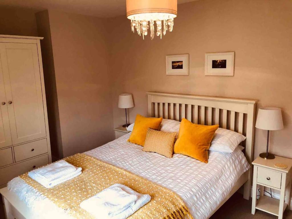 a bedroom with a bed with yellow pillows and a chandelier at Two bedroom house in central Portree in Portree