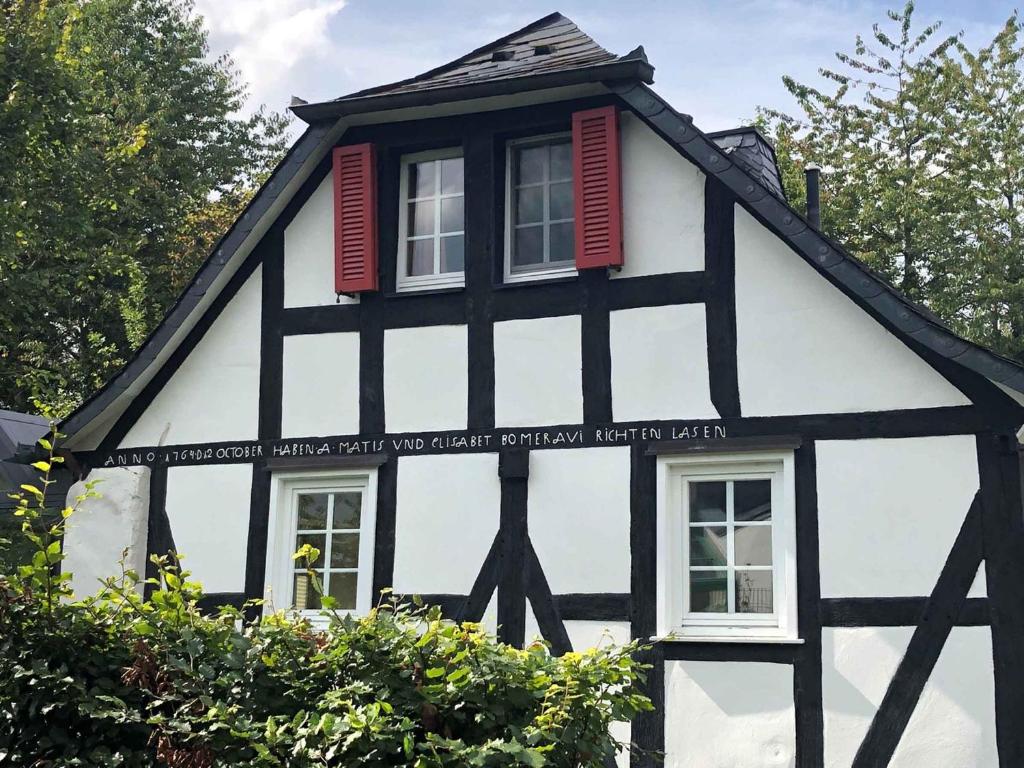 Casa en blanco y negro con ventanas con persianas rojas en Fachwerk Ferienhaus 1764, en Eslohe