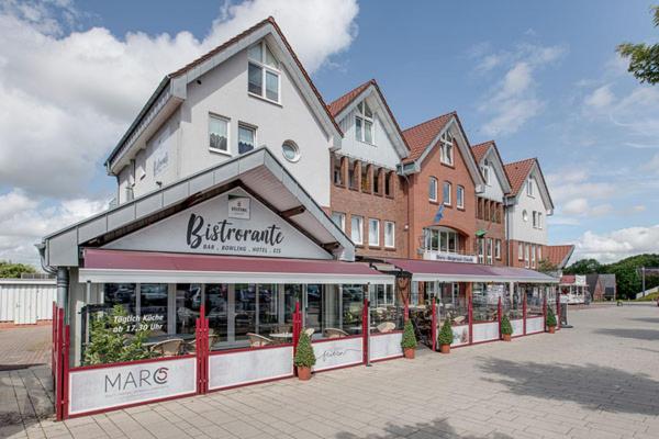 ein Geschäft vor einem großen Gebäude mit Bäumen davor in der Unterkunft MarC5 Hotel Cadenberge in Cadenberge