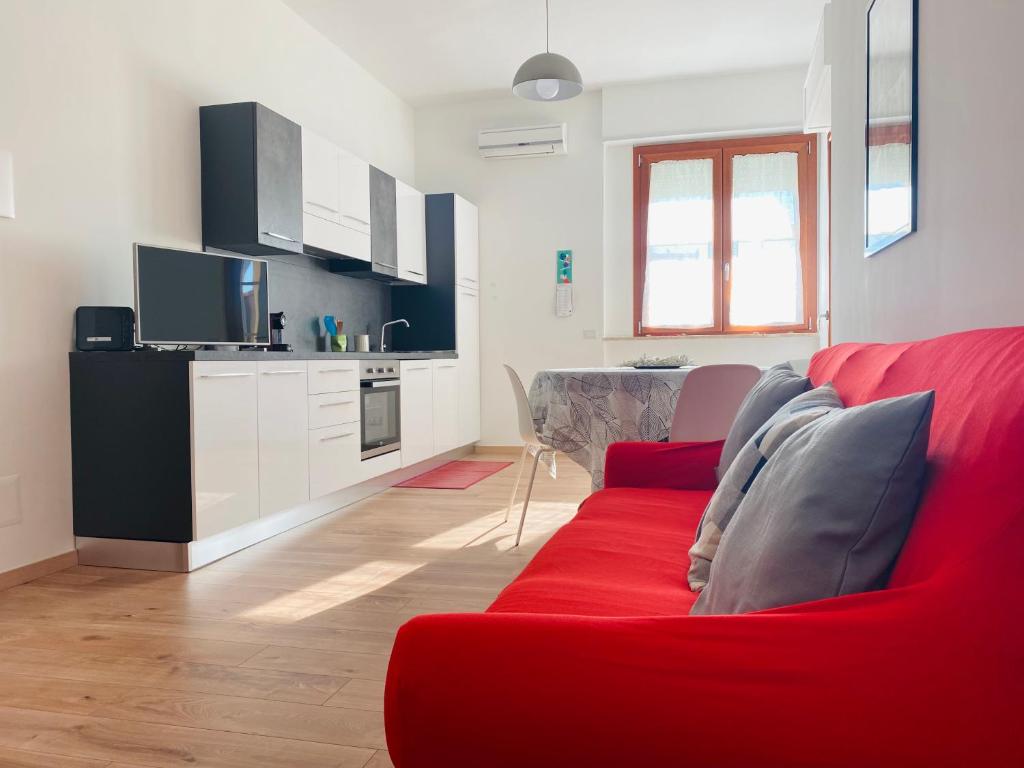 ein Wohnzimmer mit einem roten Sofa und einer Küche in der Unterkunft L'IPPOCASTANO Appartamenti - B&B in Castellaneta