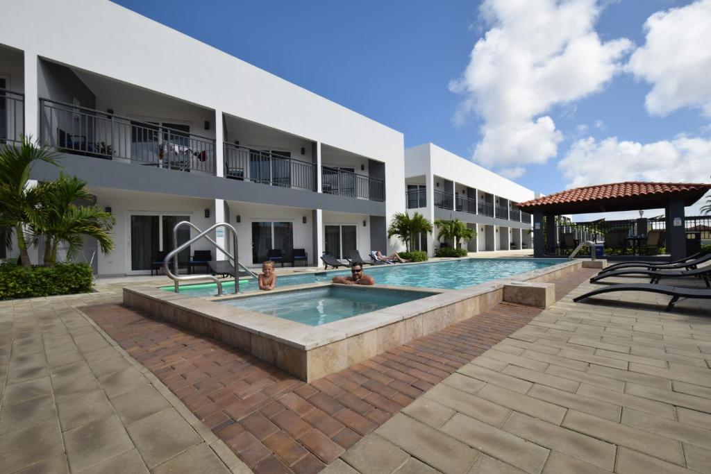 a swimming pool in front of a building at Arena Condos Aruba - few steps from Eagle Beach! in Palm-Eagle Beach