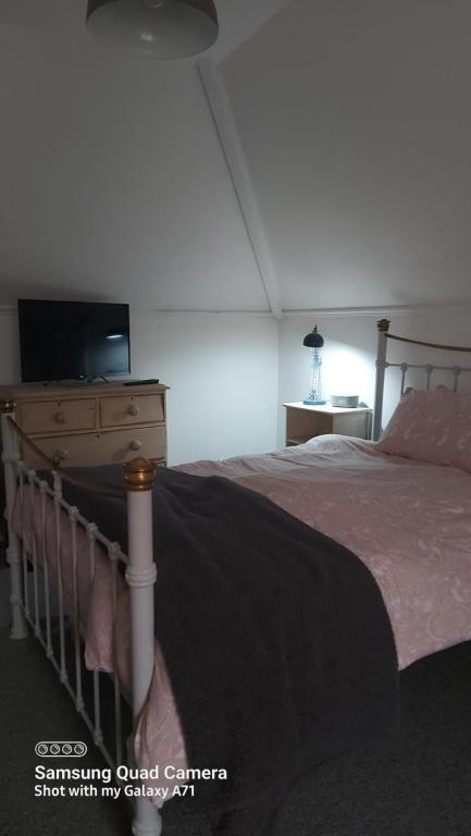 a bedroom with a bed and a dresser with a television at Homestay in Poole
