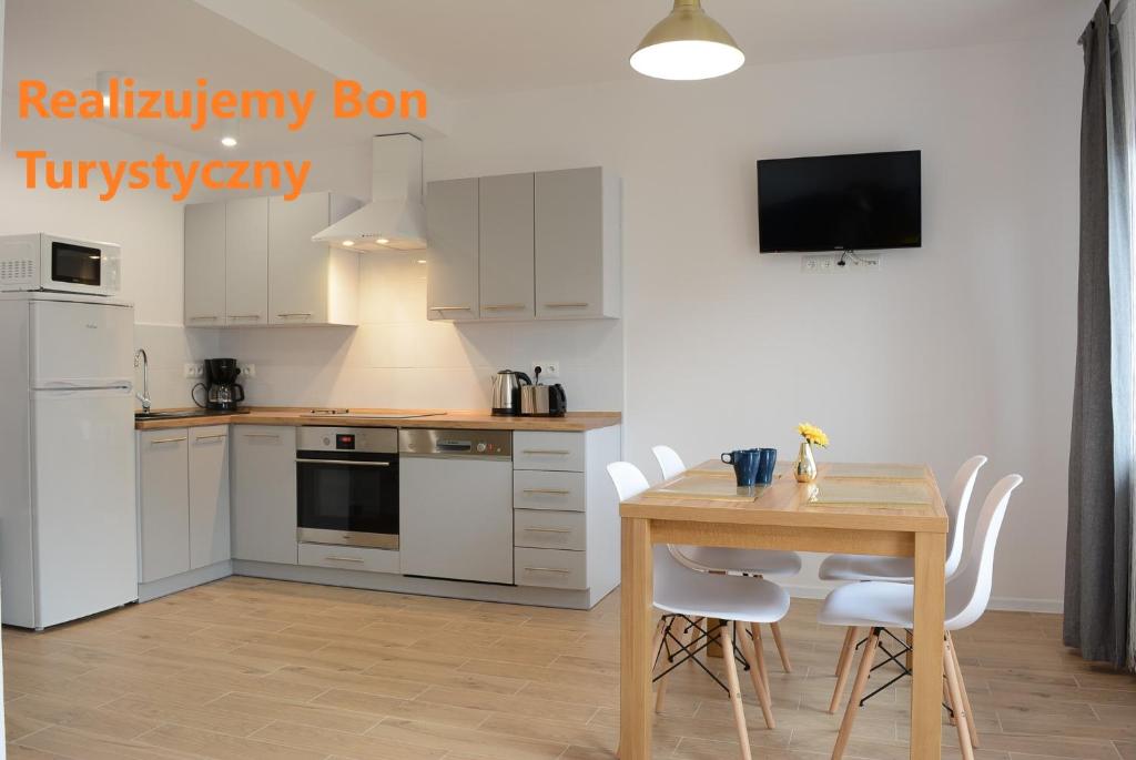 a kitchen with white cabinets and a table with chairs at Apartamenty Asturia in Rymanów-Zdrój