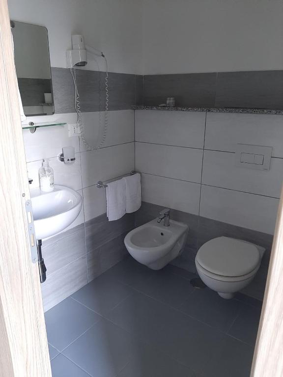 a white bathroom with a toilet and a sink at Hotel Conca d'Oro in Stalettì