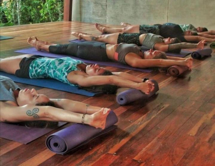 a group of women laying on the floor doing yoga at Trindade Sea and Forest Yoga Hostel in Trindade