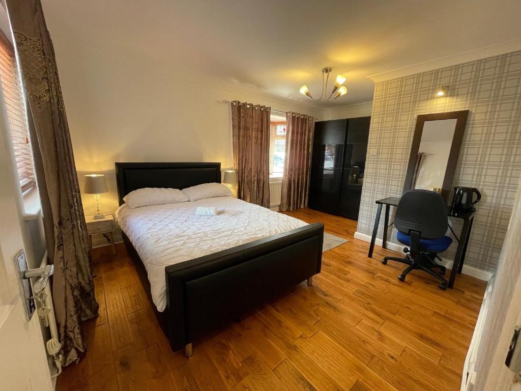 um quarto com uma cama, uma secretária e uma cadeira em ASHMINA GUEST HOUSE with Free Onsite Parking em Milton Keynes