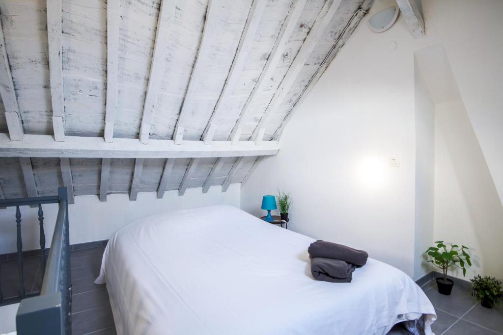 sypialnia z białym łóżkiem i drewnianym sufitem w obiekcie ROYALE APARTMENTS VIEUX LILLE 24H24H Access w Lille