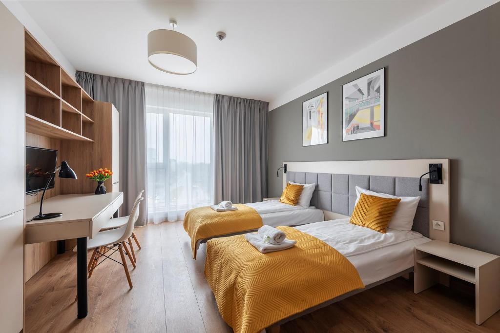 a hotel room with two beds and a desk at City Break Wolska Aparthotel in Warsaw