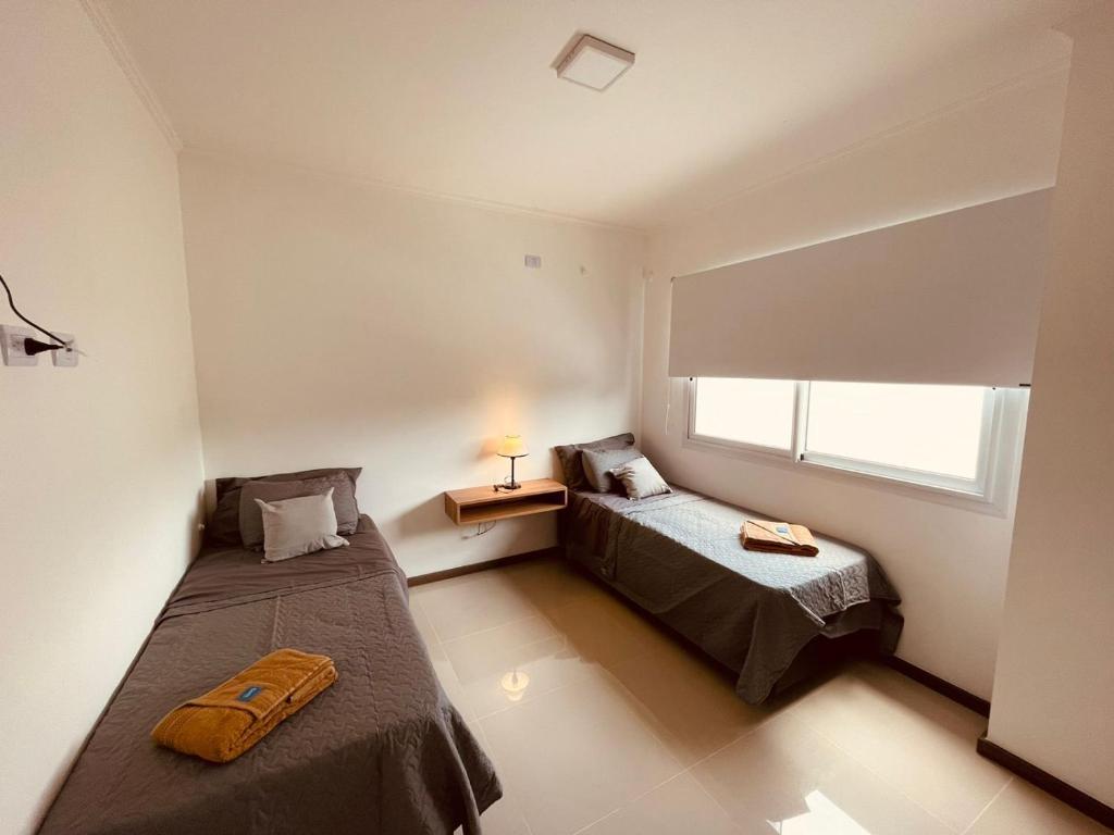 1 Schlafzimmer mit 2 Betten und einem Fenster in der Unterkunft Departamento frente al lago en Villa Carlos Paz in Villa Carlos Paz