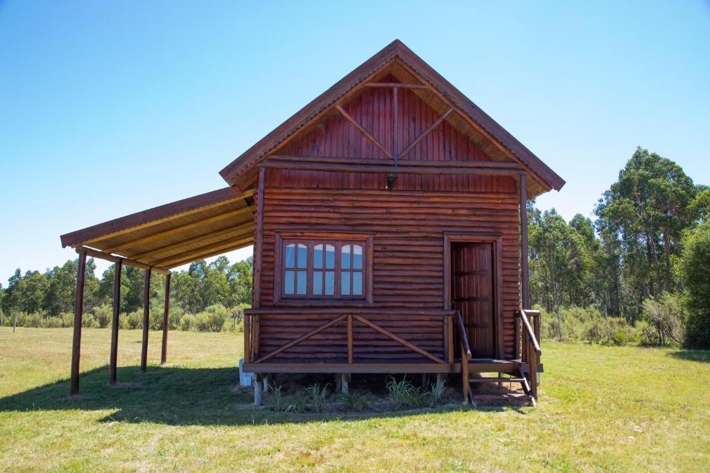 a small wooden cabin in a field of grass at Centro Los Alamos in Maldonado