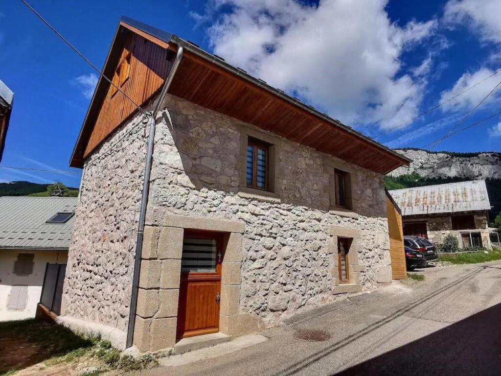 ein Steinhaus mit einer Holztür auf einer Straße in der Unterkunft L'Ophrys in Les Déserts