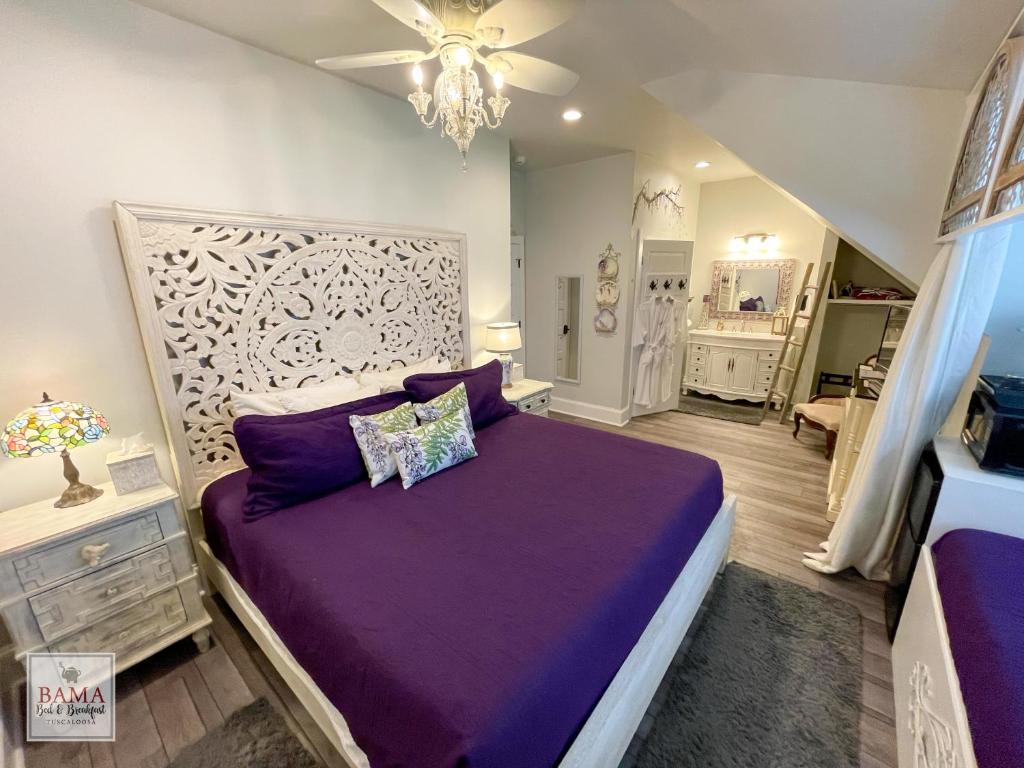 1 dormitorio con cama morada y lámpara de araña en Bama Bed and Breakfast - Wisteria Suite, en Tuscaloosa
