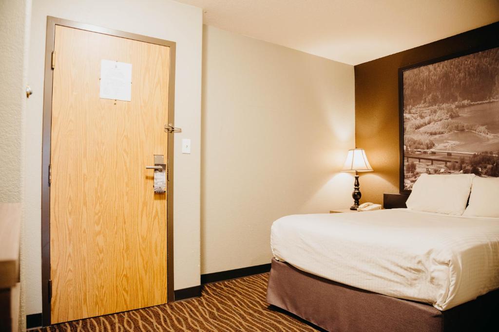 a hotel room with a bed and a door at Super 8 by Wyndham Revelstoke BC in Revelstoke