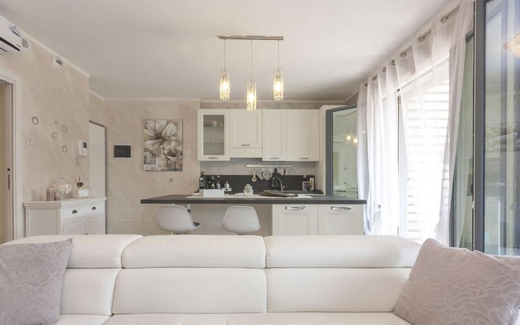 salon z białą kanapą i kuchnią w obiekcie CaseOspitali - Casa La Vela, raffinato bilocale con balcone w mieście Cernusco sul Naviglio