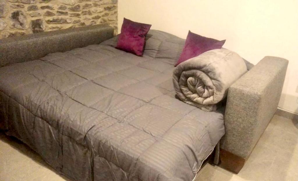 a gray bed with pillows on top of it at Atrani in Santeagueda