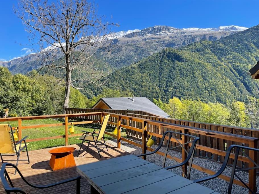 a deck with a table and chairs and mountains at Allemond - Restful 2 bed apartment for ski, cycle & family in Allemont