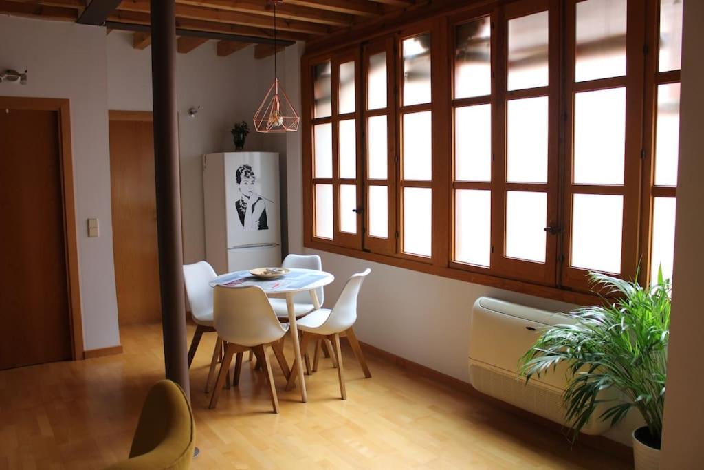 a dining room with a table and chairs and windows at La Casa de Sillería in Toledo