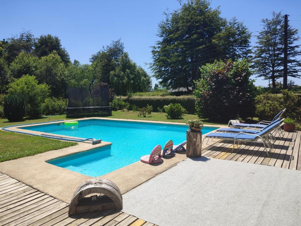 ein Pool mit einer Terrasse und einem Stuhl daneben in der Unterkunft Casa verano piscina Villarrica in Villarrica