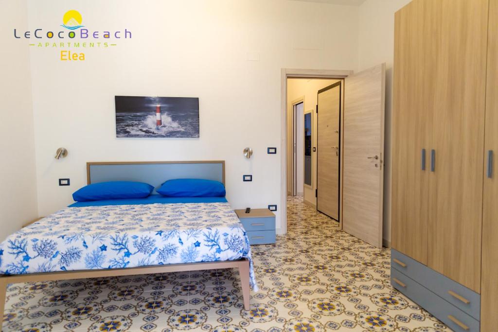 um quarto com uma cama com almofadas azuis em Le Coco Beach Apartaments em Ascea
